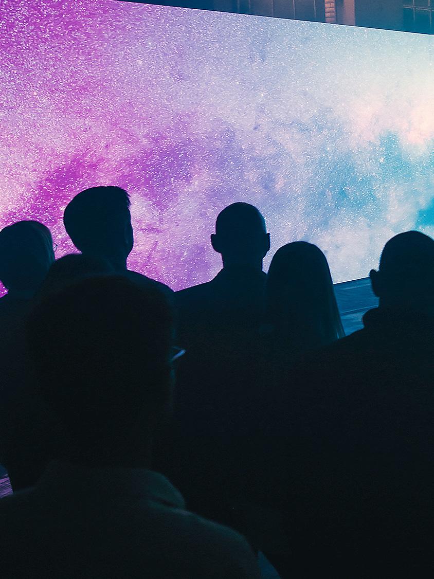 A group of people in front of a LED-Screen